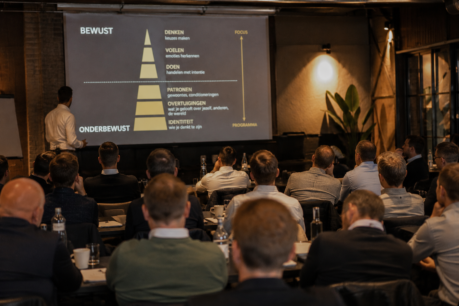 Volle zaal mannen luistert naar de spreker tijdens een seminar